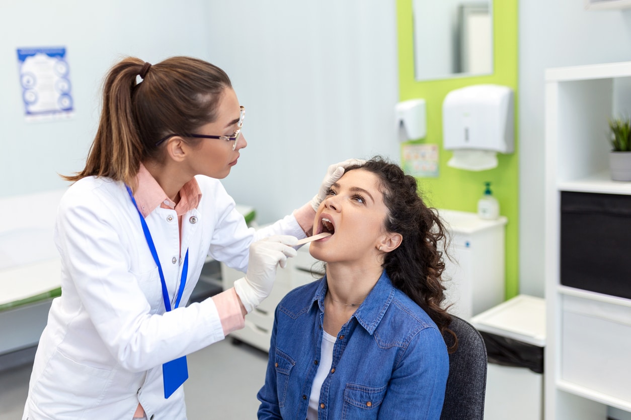 Doctor looking at a woman's tonsils. 