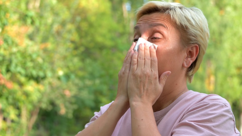 Woman blowing her nose in the park