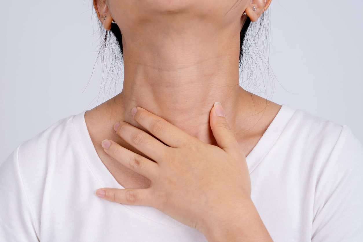 Woman holds hand to neck