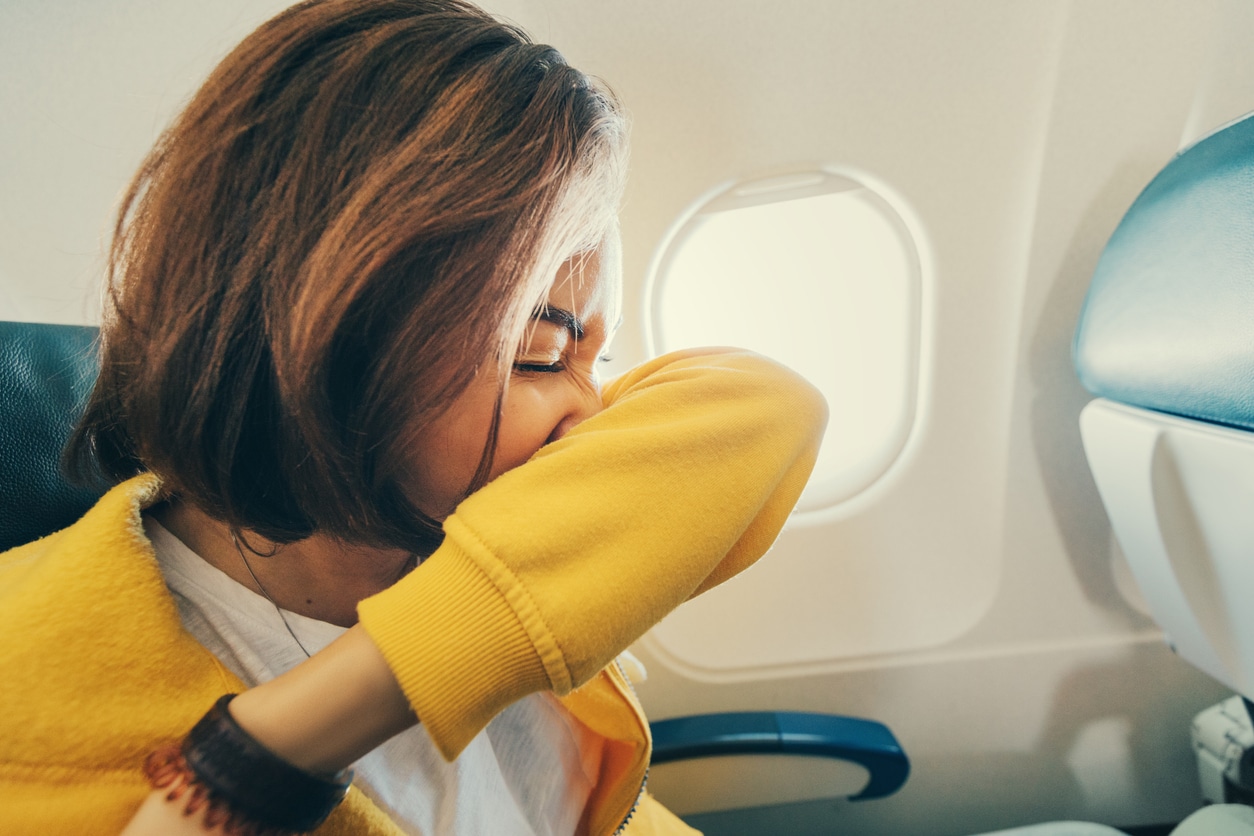 Woman sneezing on a plane