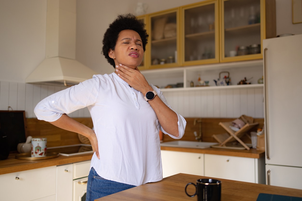 Woman with sore throat holds neck