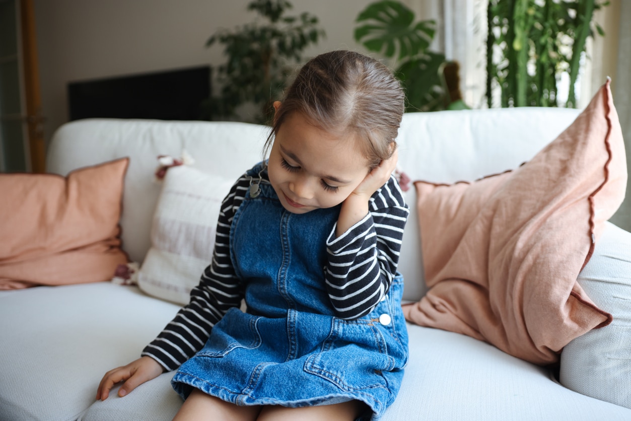 Young girl with ear infection holding her ear.