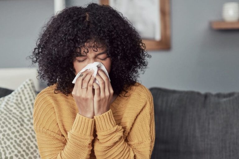 Woman dealing with allergy symptoms at home.