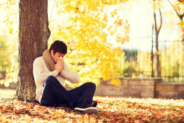 woman sneezing under tree