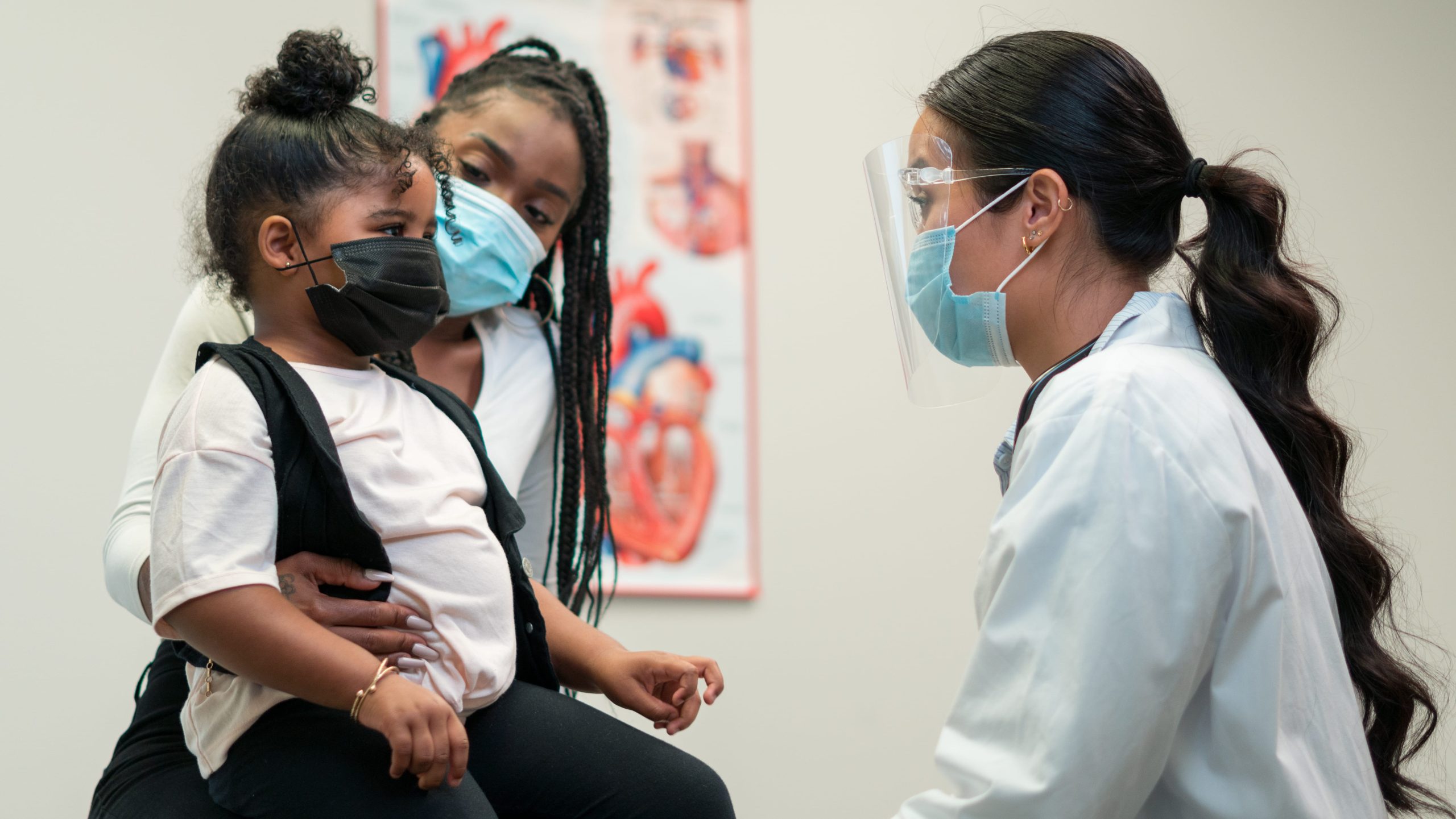 Mom and daughter visit doctor for medical advice in office setting.