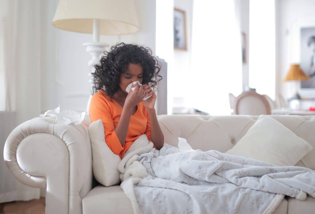 woman on couch blowing nose