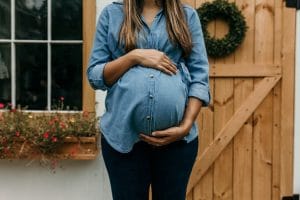 A pregnant woman in front of a house.